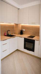 a kitchen with white cabinets and a black microwave at Cortina North Luxury Studio in Voluntari