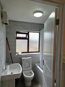 a bathroom with a toilet and a sink and a window at Chilux in Rainham