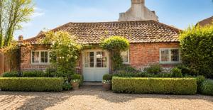 a brick house with bushes in front of it at The Stalls Suite at Strattons in Swaffham
