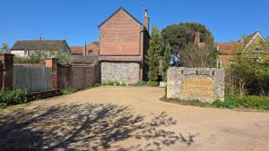 an old brick building with a sign in front of it at The Stalls Suite at Strattons in Swaffham