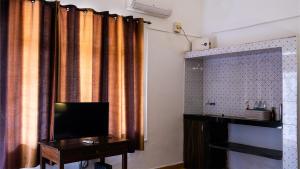 a bathroom with a television and a table and curtains at Shelter Guest House in Candolim +9 photos