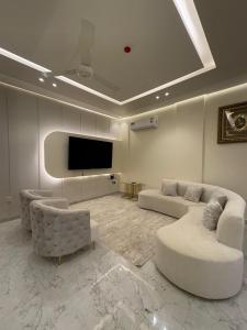 a living room with two couches and a flat screen tv at بنايه بيت الشب in Ţāqah