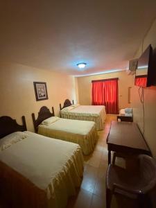 a hotel room with three beds and a television at Hotel Terraza in San Pedro Sula