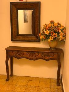 a table with a mirror and a vase with flowers on it at Hotel Terraza in San Pedro Sula
