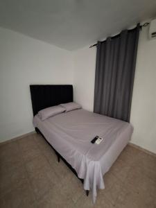 a bedroom with a bed with a black headboard and a window at Acogedor Departamento Entero in Hornillo