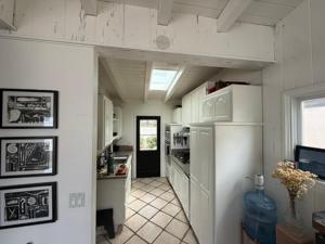 a kitchen with white cabinets and a refrigerator at Malibu Surf Cottage on Lechuza Beach in Malibu