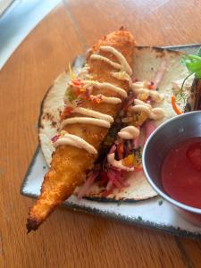 a plate of food with a fish sandwich and dipping sauce at Connemara National Park Lodge in Letterfrack