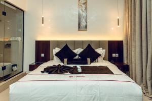 a bedroom with a large white bed with black pillows at Treal Hotels & Suites in Abeokuta