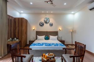 a bedroom with a bed and two chairs at Velmora Stay Premium Luxury Villa with Private Pool in Amritsar +29 photos