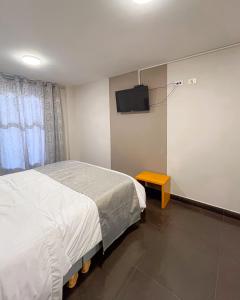 a bedroom with a bed and a tv on the wall at Hotel Centro in Cali