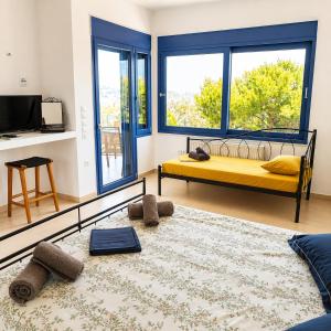 a bedroom with a yellow bed and large windows at Schinos Salty Studio in Vathí