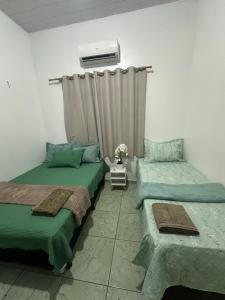 a bedroom with two beds and a window with a radiator at Apto garagem incluso in Marabá +3 photos