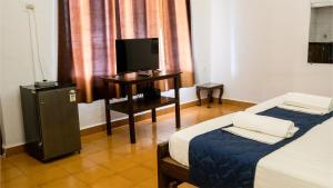 a hotel room with two beds and a television at Shelter Guest House in Candolim