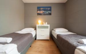 a bedroom with two beds and a dresser with a lamp at Central Sopot in Sopot