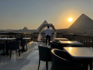 a man walking on a balcony with the pyramids in the background at Comfort Pyramids Inn in Cairo