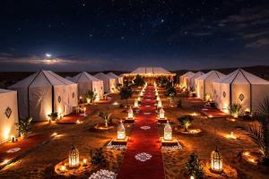 a row of tents in the desert at night at Merzouga Luxury Glamping in Merzouga