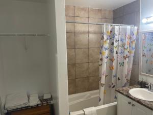 a bathroom with a shower curtain with a sink and a tub at Bayside Inn in Alert Bay +3 photos