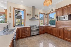 a kitchen with wooden cabinets and a sink and a stove at Three Acres, Barossa Valley in Williamstown