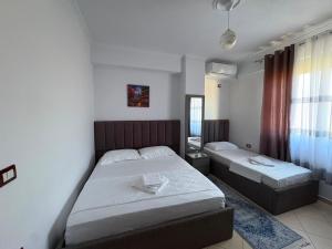 a bedroom with two beds and a window at Kapo Apartments in Gjirokastër