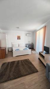 a living room with a white couch and a rug at Студио JASMIN in Tsarevo