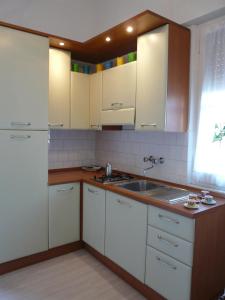 een keuken met witte kasten en een wastafel bij Appartamento Tino in Castiglione della Pescaia