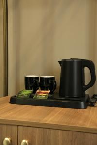 a black tea pot and two cups on a tray at Monteva Boutique Hotel in Almaty