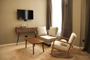 a living room with a chair and a desk with a tv at Monteva Boutique Hotel in Almaty
