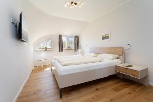 a white bedroom with a bed and a tv at Reiterhof Rickert Glücksklee in Meeschendorf