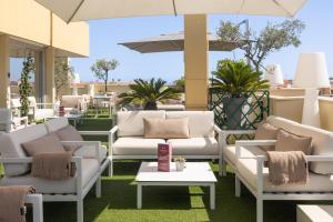 a patio with couches and tables and an umbrella at Best Western Hotel Mediterranee Menton in Menton