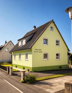a yellow house with a black roof on a street at Danube Lodge in Hüfingen