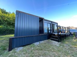 a black tiny house sitting on top of a field at Maison familiale in Froid-Chapelle