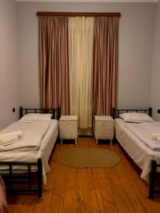 a bedroom with two beds and a window with curtains at Guest House Germani in Telavi