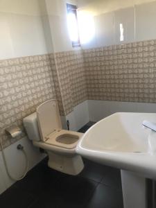 a bathroom with a white toilet and a sink at Athena Guest House in Trincomalee