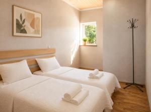two beds in a room with white sheets at Teo Guesthouse and Camping in Mestia in Mestia