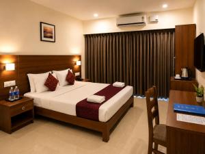 a bedroom with a bed and a desk and a television at Hotel Sandra Palace in Thekkady +40 photos