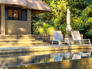two chairs and an umbrella next to a swimming pool at Beachfront Villa with Pool & Sunset Views in Rivière Noire