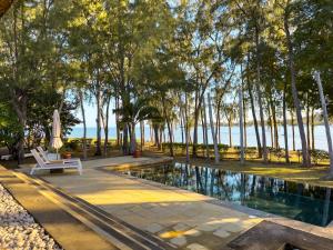 a swimming pool with a chair and an umbrella next to the water at Beachfront Villa with Pool & Sunset Views in Rivière Noire