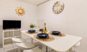 a white table with chairs and a clock on the wall at Relax Apartment Backnang in Backnang