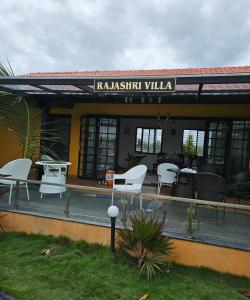 a restaurant with white chairs and tables in front of it at Rajashree Multipurpose Resort in Solapur