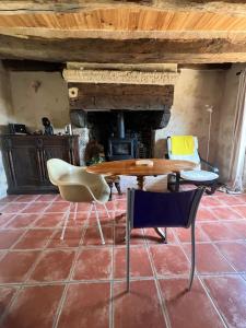 a table and chairs in a room with a fireplace at La Maison du Tisserand maison entière à Bécherel in Bécherel