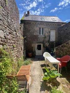 a stone house with a table and chairs in front of it at La Maison du Tisserand maison entière à Bécherel in Bécherel +4 photos