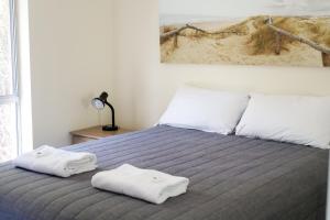 a bedroom with a bed with two towels on it at Robe Sunset Apartments in Robe
