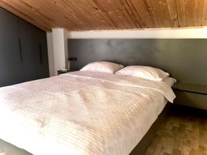 a bedroom with a white bed with a wooden ceiling at RestList in Haghpat