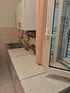 a kitchen counter with a sink and a window at Bosiljak in Zelenika