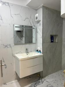 a white bathroom with a sink and a mirror at Xhani Boutique Rooms in Durrës +46 photos