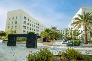 a large building with palm trees in a courtyard at MGM Service Apartment by Savills Oman in Muscat