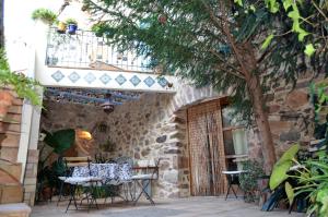 un patio con mesas, sillas y un árbol en La Casa Del Teix en Eslida