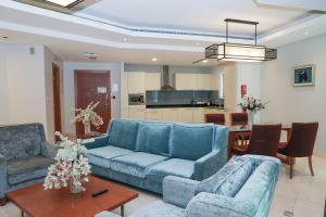 a living room with blue couches and a table at MGM Service Apartment by Savills Oman in Muscat
