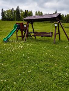 a playground with a slide and a bench in a field at Cabana Elena in Gârda de Sus