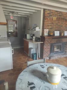 a kitchen with a table and a brick fireplace at Les Rosiers in Onjon